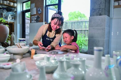 在江苏省昆山市锦溪镇理想村，创业者为一名小游客示范陶器制作。新华社发