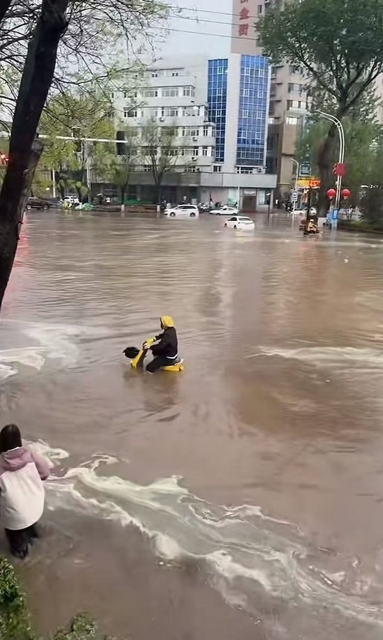 行人在没过膝盖的积水中艰难行走。图/社交平台