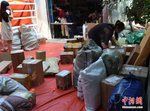 资料图：工作人员正在整理送到快递点的包裹。 周毅 摄