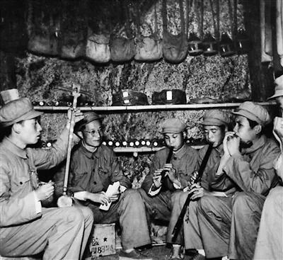 《歌唱祖国》的作者王莘（左二）在抗美援朝战场防空洞内教志愿军战士演奏这首歌曲。&nbsp;