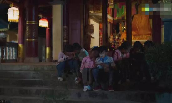 低头玩手机的孩子和他们背后沉默的佛祖。/&nbsp;电影《米花之味》