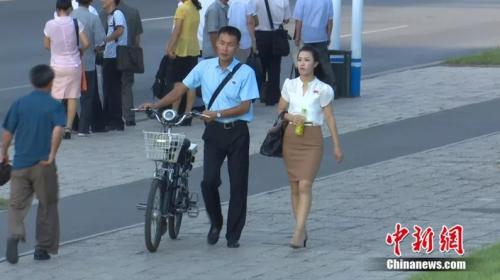 朝鲜小伙和姑娘的左胸口都佩戴领袖胸章。中新网视频截图