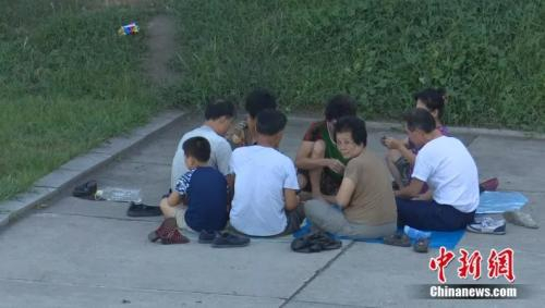 老人铺了毯子，坐着打牌。中新网视频截图