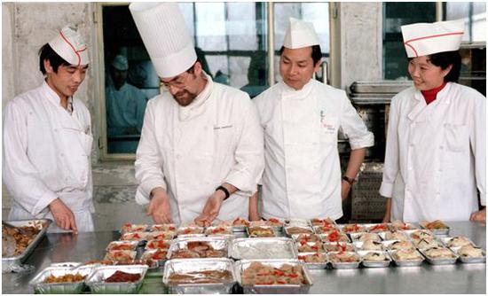 ▲&nbsp;北京航空食品公司厨师长、法国人孟培沙（左二）和助理厨师长、香港同胞邓耀全（右二）等在一起研究航空菜肴的配制（1986年5月摄）。&nbsp;