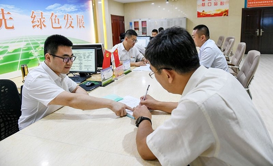 　　△ 2019年7月16日，在内蒙古自治区自然资源厅的自然资源政务大厅内，办事员（左）为采矿企业办理相关审批手续。