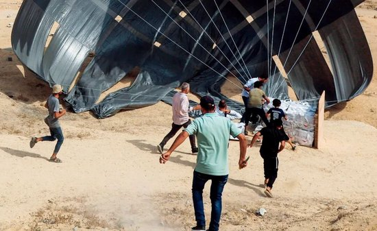8月12日，在加沙地带中部代尔拜拉赫，人们跑向援助物资空投地点。