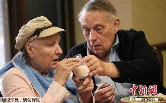  一名老人在照顾自己患有阿尔兹海默症的妻子。