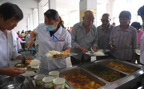 7月28日中午，在巢湖市柘皋镇柘皋中学群众安置点，工作人员正在为安置群众提供免费午餐。记者 苏玲 摄