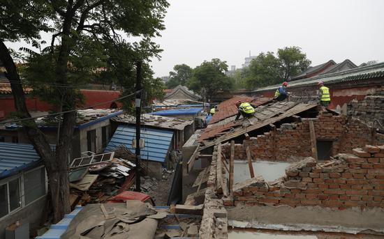 施工工人在拆除房屋屋顶砖瓦。摄影/新京报记者 侯少卿