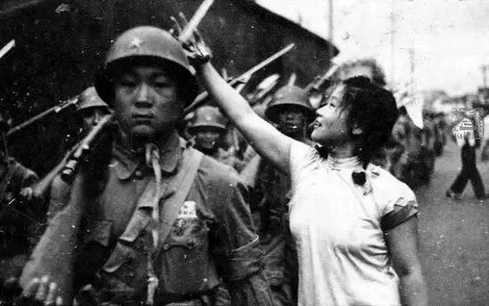 ▲杭州解放时，武林门附近，身着旗袍的纺织女工为解放军戴花