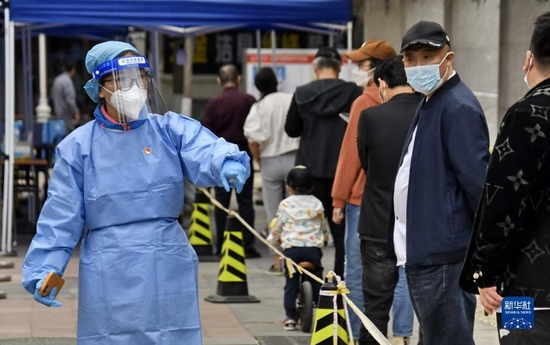 共产党员、北京八里庄街道机关干部张茜（左）在核酸筛查现场进行秩序维护（2022年5月11日摄）。新华社记者 李欣 摄