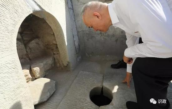 俯身察看石景山上的文物古井