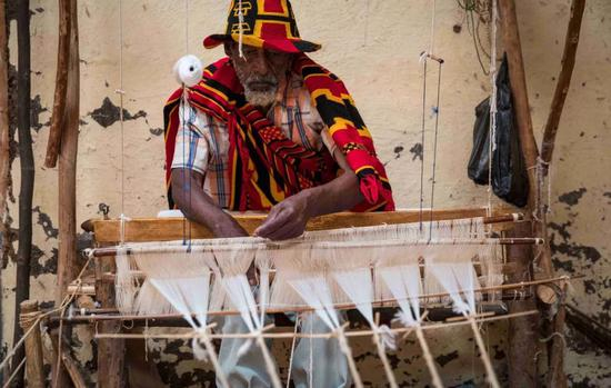  一位都则族老人在纺布