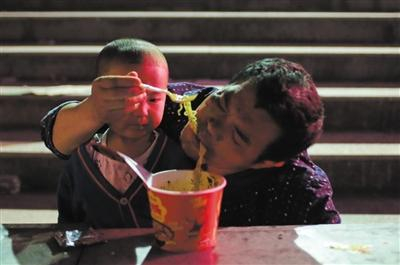 8月9日，受九寨沟地震影响，滞留的游客和外来务工人员被安置在文化广场。一对爷孙在安置点吃晚餐。新京报记者 王飞 摄