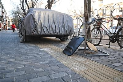 　　12月15日，东城区夕照寺街，一辆小轿车停在盲道上，一把坏掉的椅子被扔在盲道边。新京报记者 王嘉宁 摄