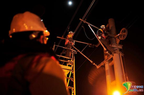 刘帅正在检查接触网补偿装置铁坠砣，接触网线受温度影响热胀冷缩变化较大，需要通过调整铁坠砣的高度进行接触网线张力的调整。中国青年网记者　刘尚君摄