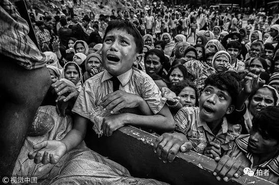 　　2017年9月20日： 孟加拉国吉大港区的科克斯巴扎尔县（Cox‘s Bazar），非政府组织在Balukali难民营附近派发食物，一名罗兴亚难民男孩爬上非政府组织的货车上，边哭泣边等待领取食物。&nbsp;