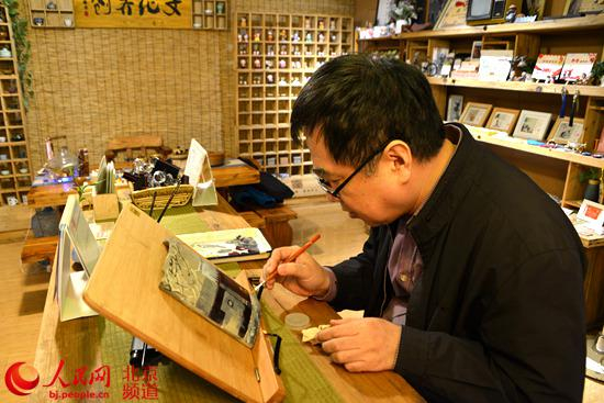 史家胡同老居民张迎星用画笔在瓦片上绘制胡同的变迁。 人民网孟竹 摄