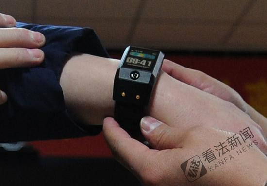 图为监狱民警为离监探亲的服刑人员佩戴电子手环 。摄/记者 林晖