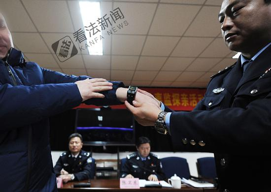 图为监狱民警为离监探亲的服刑人员佩戴电子手环 。摄/记者 林晖