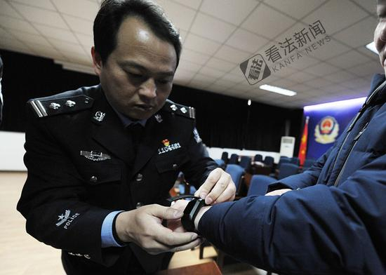 图为监狱民警为离监探亲的服刑人员佩戴电子手环 。摄/记者 林晖