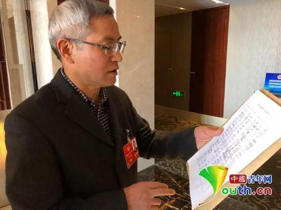 全国政协委员贺云翱发起这份联合提案，图为提案最终递交前他向记者介绍签名情况
