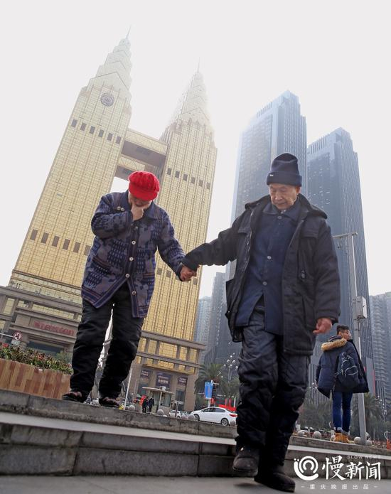 老人小心翼翼地牵着老伴下梯坎