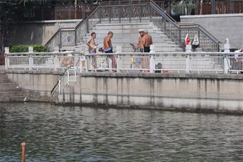 ▲8月25日，东二环护城河，几位游泳者上岸后聊天。 新京报记者 王飞 摄