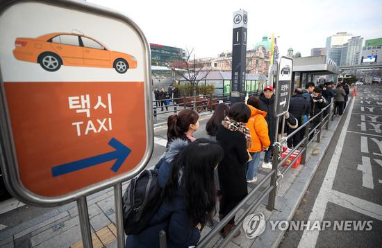 20日上午，首尔市民在出租车站点排长队等车。（韩联社）