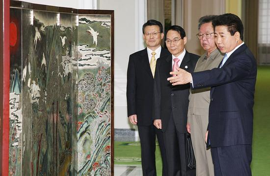 　　2007年10月2日，朝鲜平壤，时任韩国总统卢武铉（右一）与时任朝鲜最高领导人金正日（右二）正在观看卢武铉赠送的屏风。