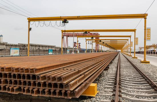 铺架基地材料堆场内，钢轨和水泥枕木整齐的堆放在运输轨道边。这些材料最终在预组装完成后，会被列车运往格库铁路的铺架现场，成为格库铁路线的一部分。