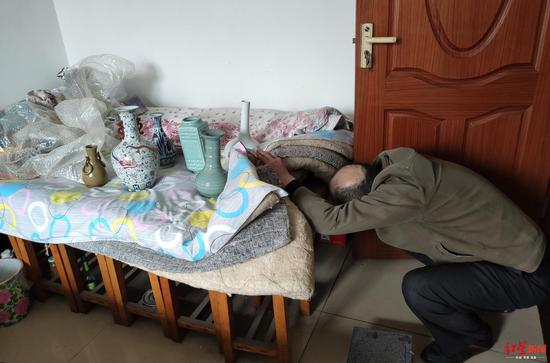 徐大爷从床底下将购买的假古董拿到床上