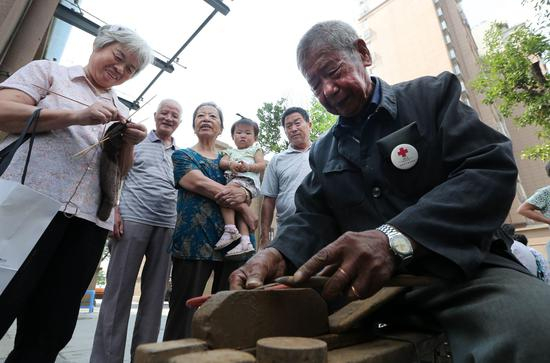 吴锦泉为社区居民磨刀（新华社）