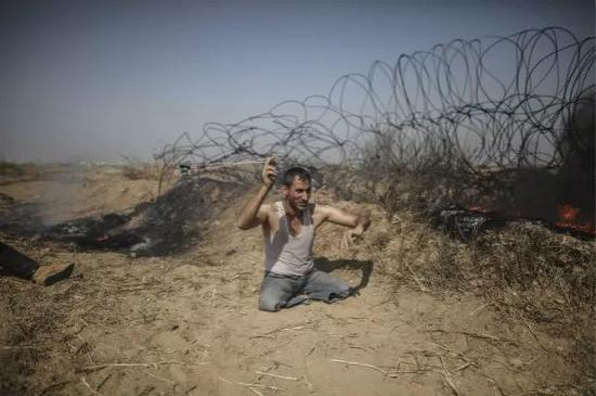 　　5月11日，在加沙地带东部与以色列接壤的边境地区，一名双腿残疾的巴勒斯坦示威者向以色列士兵投掷石块。