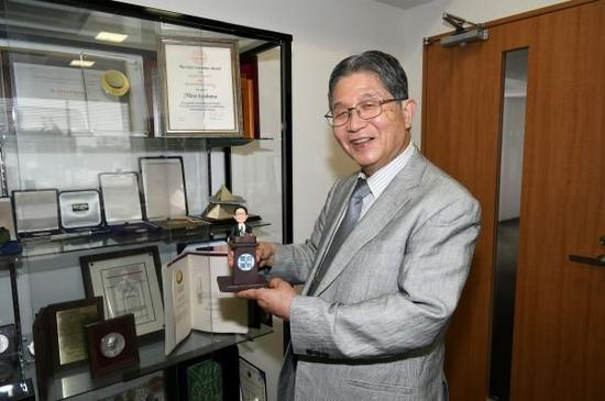 藤岛昭展示在上海交大进行学术交流时获赠的自己动漫形象礼物（华义 摄）