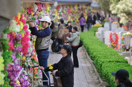 前来祭祀的市民在为墓碑挂上花圈。新京报记者 郑新洽 摄
