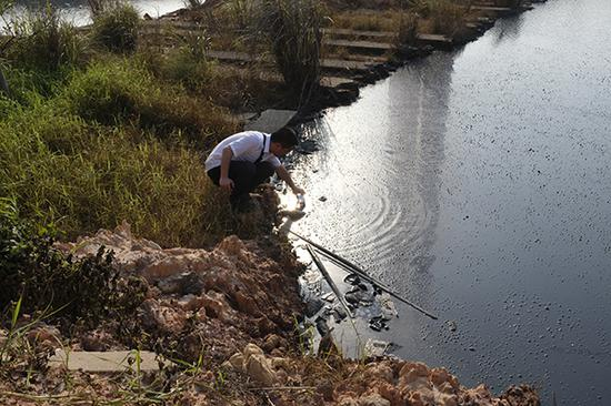 　　6月9日，钦州钦南区一家土法炼铝企业正在生产，厂区蓄积大面积刺鼻废水，通过管道外拍河流。图为督察人员正取样检测。本文图均为澎湃新闻记者 刁凡超 图