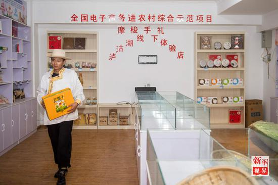 ↑摩梭青年次里打史在宁蒗永宁乡落水村的电子商务体验店里整理商品。新华社记者胡超摄