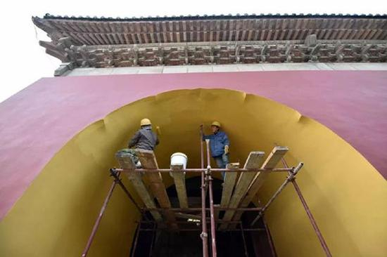 工人们正在修复天坛广利门，在城门内侧涂上特别颜色的涂料，还原历史原貌。
