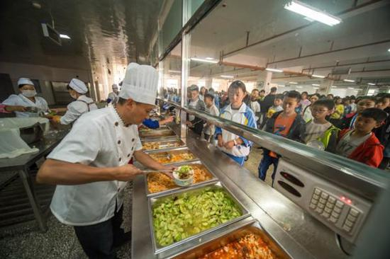  学生在会泽县以礼中学的食堂里排队打午餐。胡超 摄