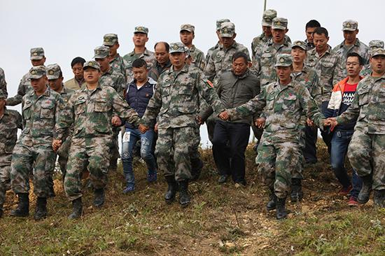 　　2016年11月，扫雷三队组织文山州富宁县田蓬镇雷场移交仪式现场，官兵们手拉手对雷场进行踏勘检验。黄巧 摄