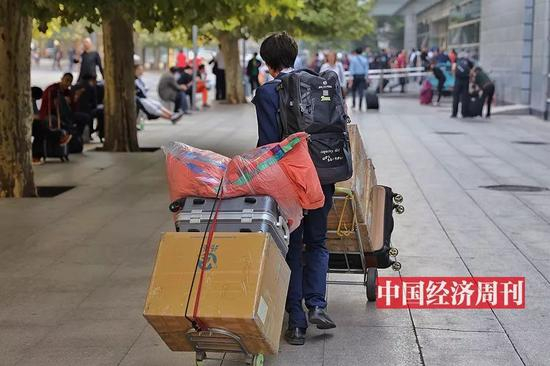 一位拖着厚重行李的旅客（《中国经济周刊》首席摄影记者 肖翊 | 摄）