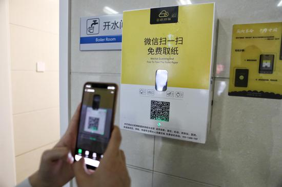 今年4月16日，北京安贞医院门诊楼厕所外，一名女士在用微信扫码取纸。摄影/新京报记者 王嘉宁