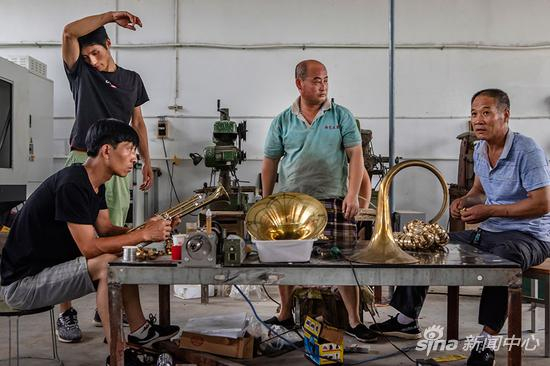 谭封庄村博烨乐器配件加工厂，闫小旺（右一）在和工人们检测配件精度。摄影/赵亢