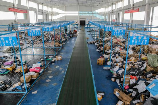 南疆快递物流园快件中转分拣车间，成堆的快件经过分拣整理将被送往各个区县乡镇。