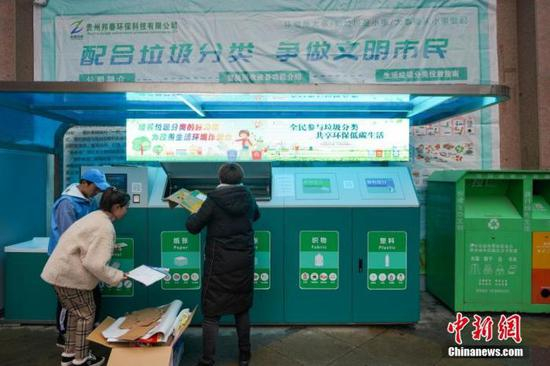 　　资料图片为：11月26日，在贵阳市花果园社区，两位贵阳市民在工作人员的帮助下进行垃圾分类投放。中新社记者 贺俊怡 摄