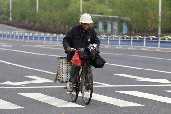 吴锦泉骑车外出磨刀（新华社）