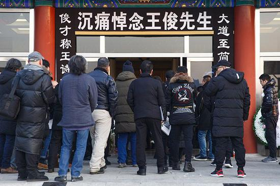 　前来悼念的亲友排队进入礼堂。