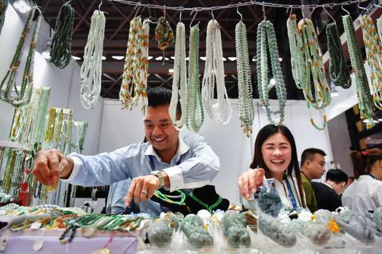 　　▲2018年9月12日，第十五届中国—东盟博览会在中国广西南宁国际会展中心举行。图为两名缅甸参展商在展示饰品。