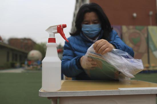 家长领完教材在检查书籍，旁边放有酒精可以消毒。摄影/新京报记者 浦峰